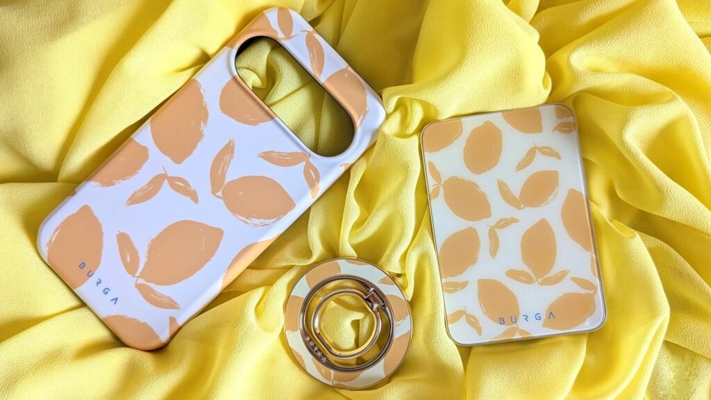 Burga phone case with a lemon pattern, phone stand, and matching accessories on a yellow fabric background.