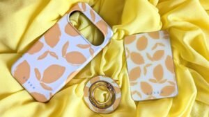 Burga phone case with a lemon pattern, phone stand, and matching accessories on a yellow fabric background.